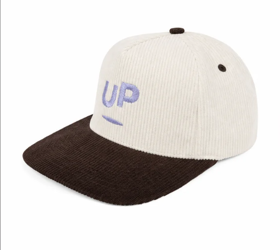 Three-quarter view of the cream and brown corduroy UP cap with flat brim